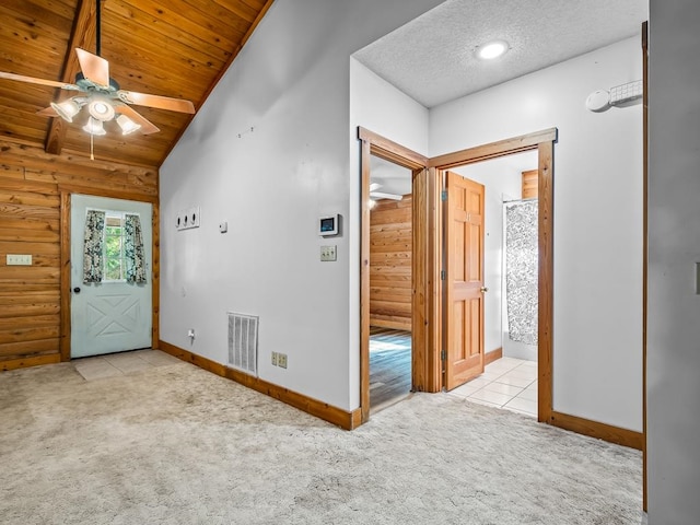 carpeted foyer entrance with wood walls, lofted ceiling, a textured ceiling, and ceiling fan