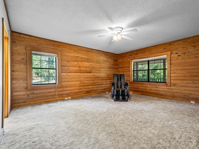 interior space featuring wooden walls, a textured ceiling, ceiling fan, and carpet floors