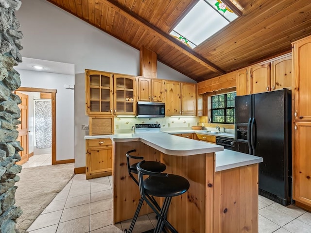 kitchen featuring black appliances, a kitchen island, a breakfast bar area, a skylight, and wooden ceiling