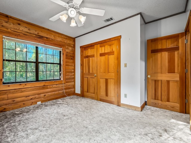 unfurnished bedroom with a closet, ornamental molding, a textured ceiling, carpet flooring, and ceiling fan