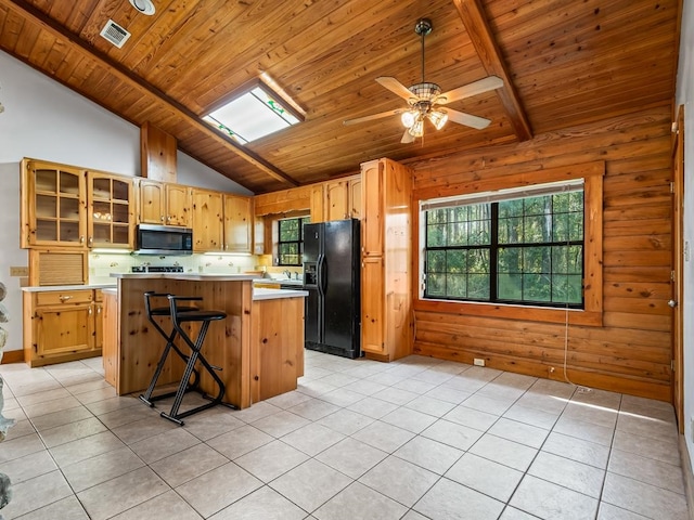 kitchen featuring a kitchen island, black fridge, wooden walls, and plenty of natural light