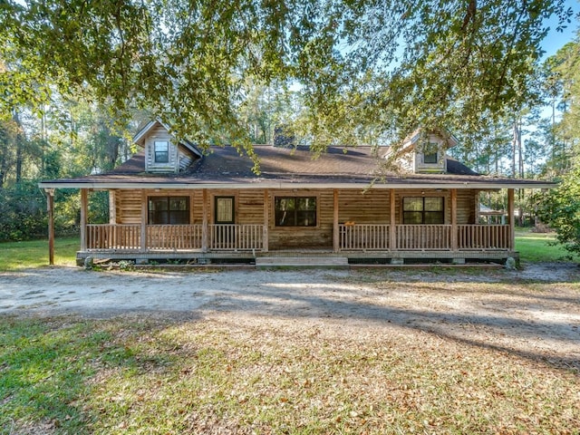 log cabin featuring covered porch and a front lawn