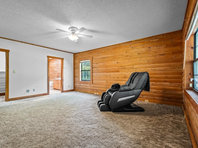 sitting room with ceiling fan, a textured ceiling, and wooden walls