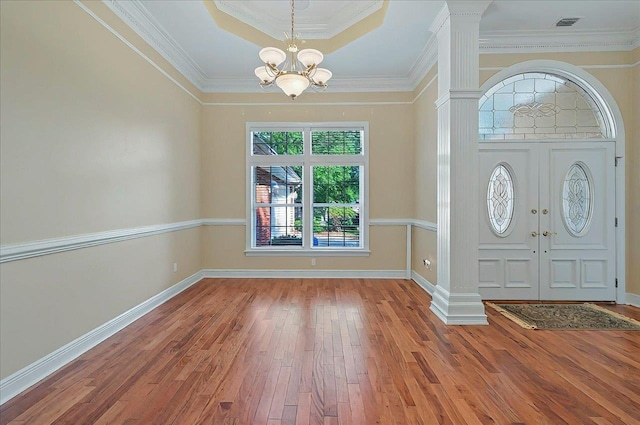 foyer entrance with an inviting chandelier, ornamental molding, decorative columns, and hardwood / wood-style floors