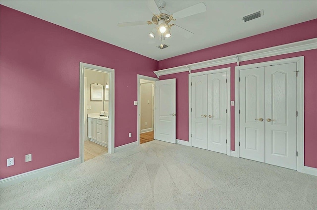 unfurnished bedroom with light carpet, ensuite bath, two closets, baseboards, and visible vents