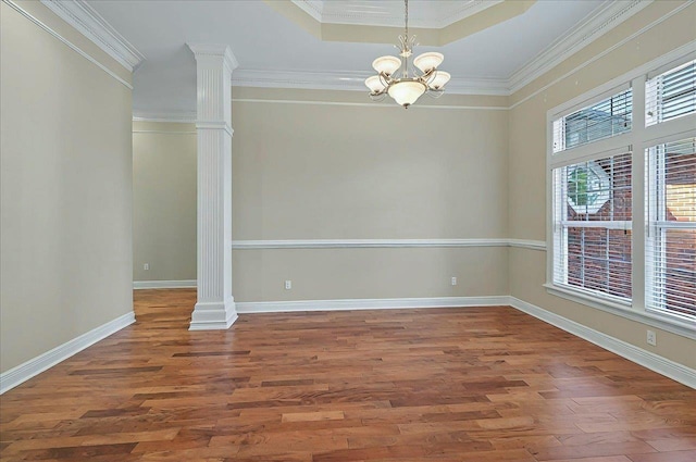 unfurnished dining area with crown molding, decorative columns, a chandelier, and wood finished floors