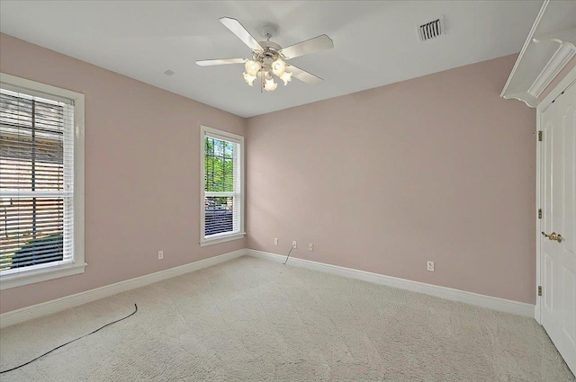 unfurnished room featuring baseboards, visible vents, a ceiling fan, and light colored carpet