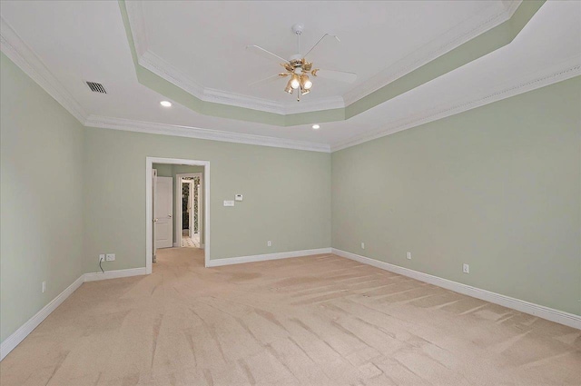 unfurnished room with ceiling fan, light colored carpet, a raised ceiling, visible vents, and ornamental molding