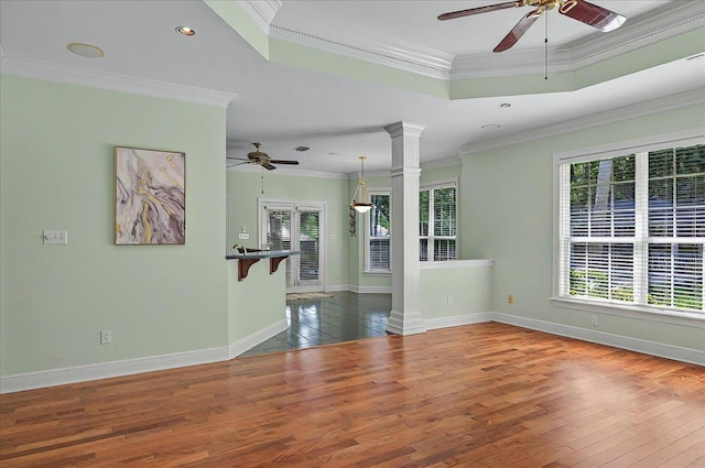 unfurnished room with ornate columns, baseboards, ceiling fan, and wood finished floors