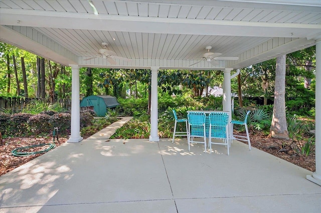 view of patio featuring an outdoor structure, ceiling fan, a shed, and outdoor dining space