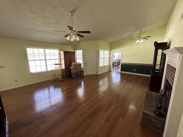 unfurnished living room featuring a fireplace, dark wood-type flooring, ceiling fan, and vaulted ceiling