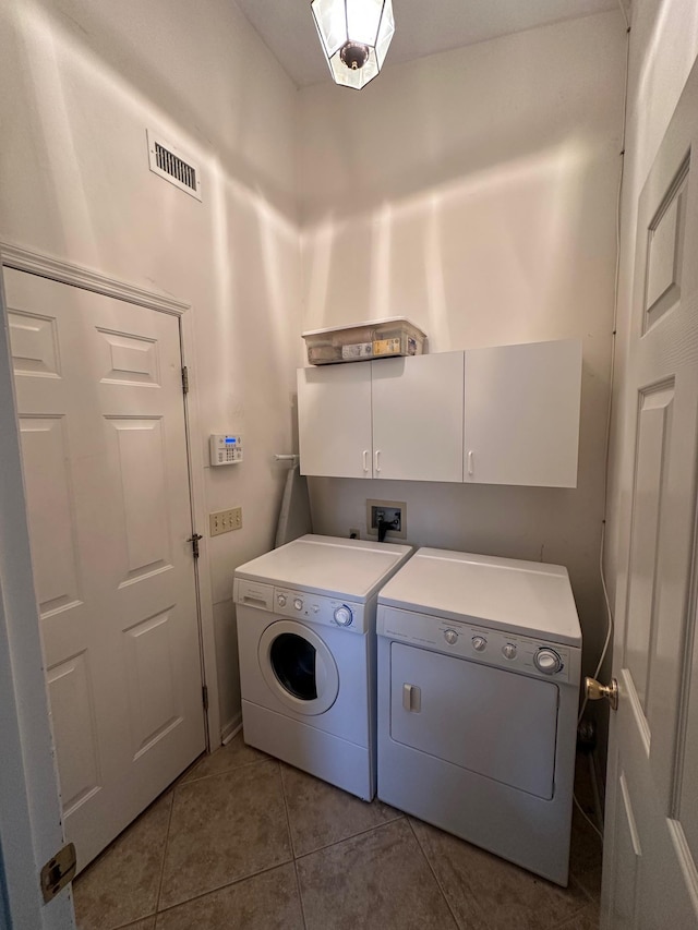 laundry area featuring tile patterned floors, visible vents, cabinet space, and washing machine and clothes dryer