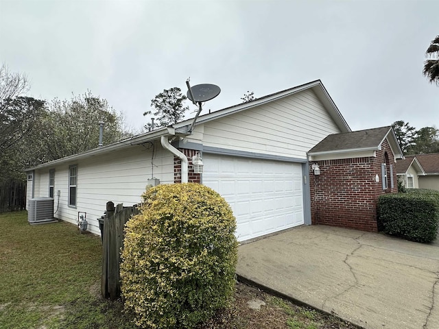 view of property exterior featuring brick siding, central AC unit, driveway, a yard, and an attached garage