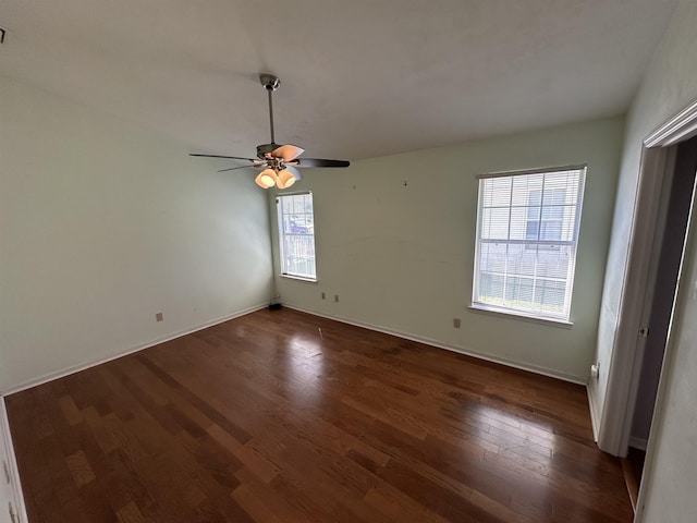 spare room with baseboards, a ceiling fan, and dark wood-style flooring