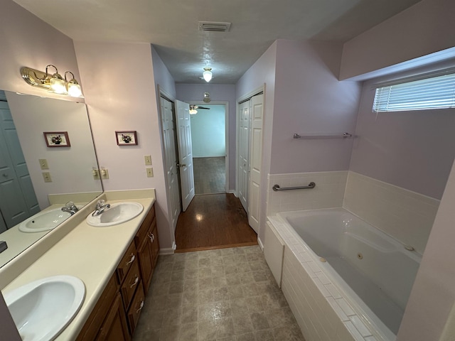 bathroom with double vanity, a tub with jets, and a sink