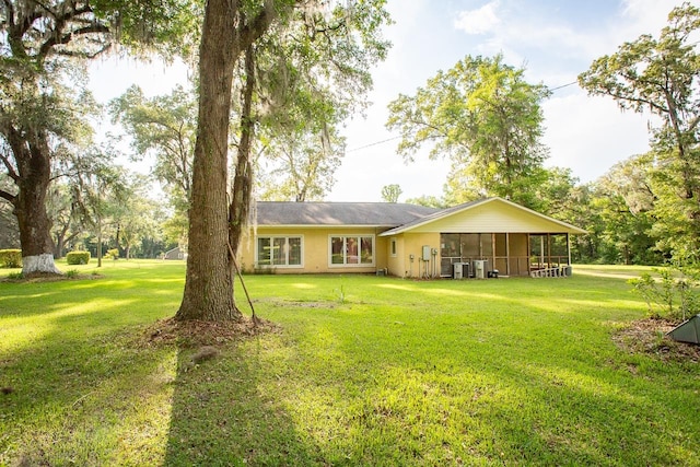 rear view of property featuring a lawn and a sunroom