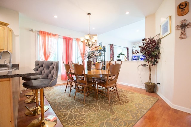 dining room with sink, wood-type flooring, and a notable chandelier