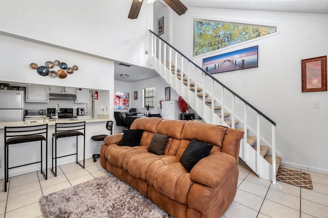 living area with light tile patterned floors, ceiling fan, stairway, and visible vents