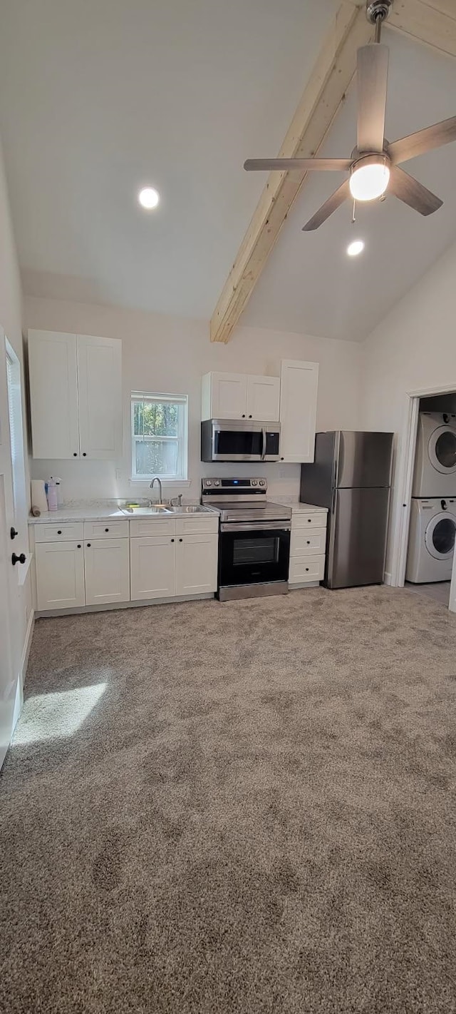 kitchen featuring stacked washer and clothes dryer, sink, vaulted ceiling with beams, stainless steel appliances, and white cabinets