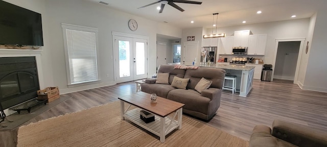 living room with french doors, ceiling fan, and light hardwood / wood-style flooring