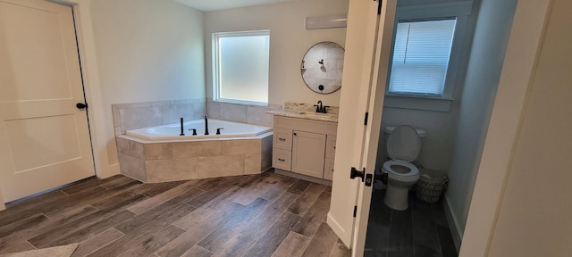 bathroom with vanity, a relaxing tiled tub, and toilet