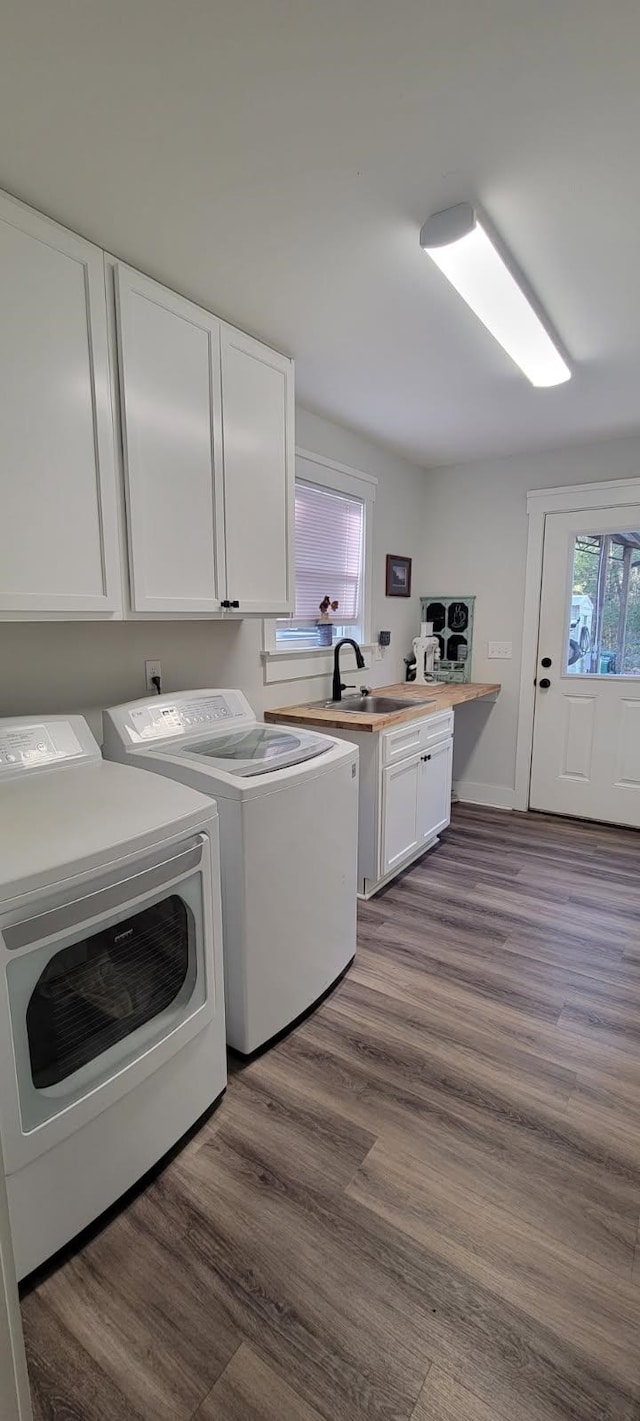 clothes washing area featuring cabinets, separate washer and dryer, hardwood / wood-style flooring, and sink