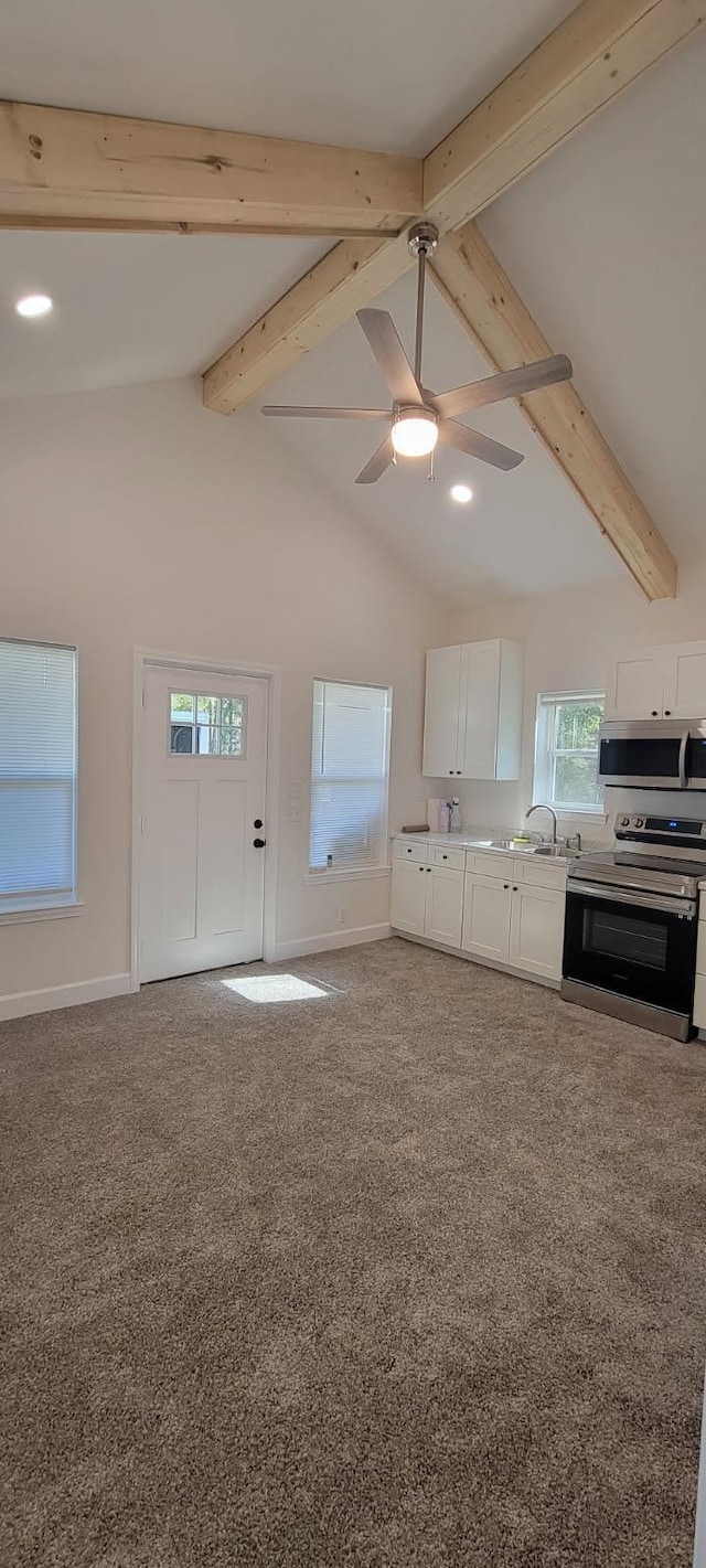 kitchen featuring appliances with stainless steel finishes, carpet flooring, vaulted ceiling with beams, white cabinets, and ceiling fan