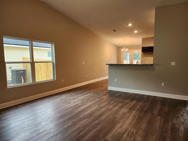 unfurnished living room featuring dark wood-type flooring, vaulted ceiling, and an inviting chandelier