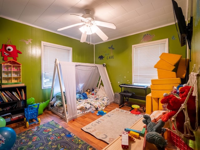 bedroom with hardwood / wood-style floors, ornamental molding, and ceiling fan