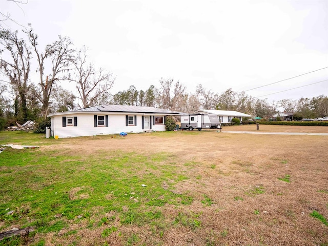 view of front of home with a carport, a front yard, and solar panels