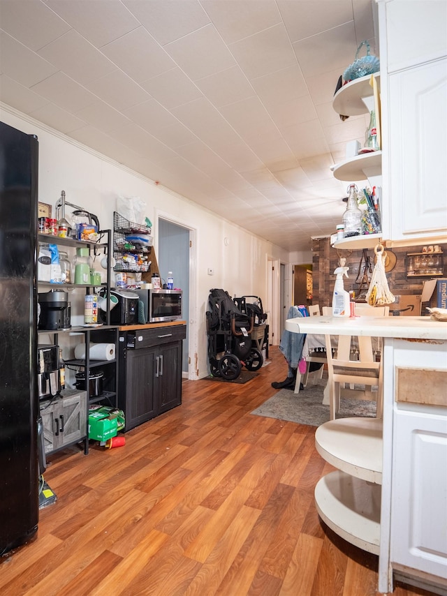 interior space with white cabinetry, black refrigerator, and light hardwood / wood-style floors