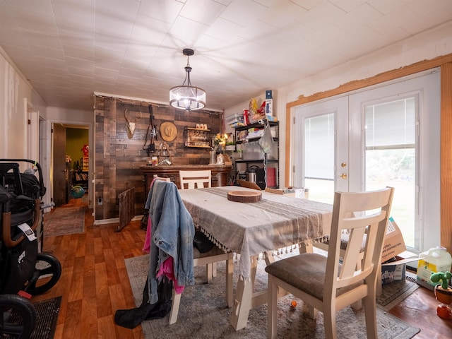 dining space featuring wood-type flooring, wood walls, and french doors