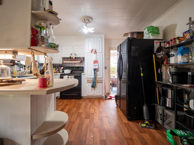 kitchen with white cabinetry, backsplash, a kitchen bar, black appliances, and light hardwood / wood-style flooring