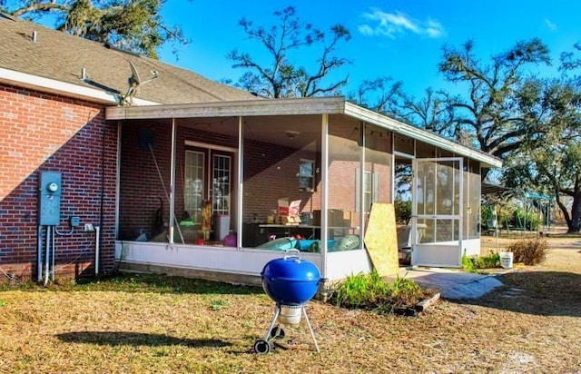 rear view of house featuring a sunroom and a lawn