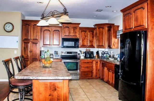 kitchen featuring hanging light fixtures, a kitchen breakfast bar, a center island, black appliances, and light tile patterned flooring