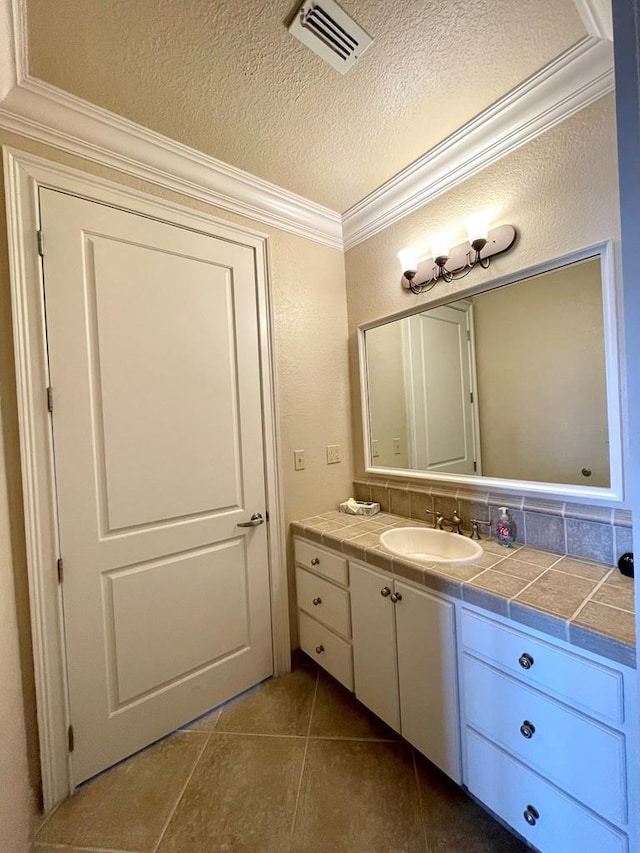 bathroom with vanity, a textured ceiling, tile patterned floors, and crown molding