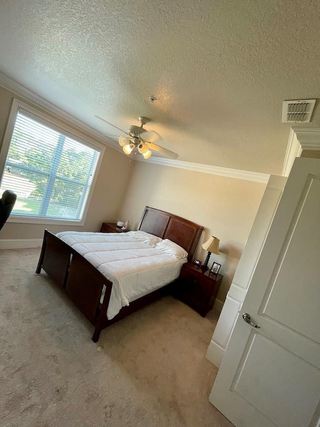 carpeted bedroom featuring a textured ceiling, ornamental molding, and ceiling fan