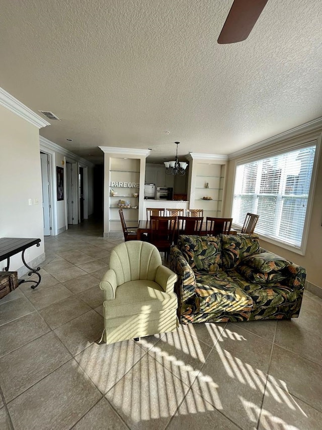 living room featuring ornamental molding, ceiling fan with notable chandelier, and a textured ceiling