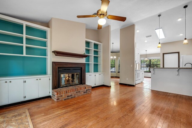 2825 Ohara Dr, Tallahassee, FL 32309 - unfurnished living room with light wood-style flooring, a ceiling fan, a brick fireplace, and a chandelier