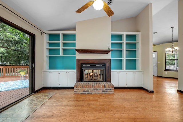 2825 Ohara Dr, Tallahassee, FL 32309 - unfurnished living room with vaulted ceiling, a ceiling fan, light wood-style floors, a fireplace, and a chandelier