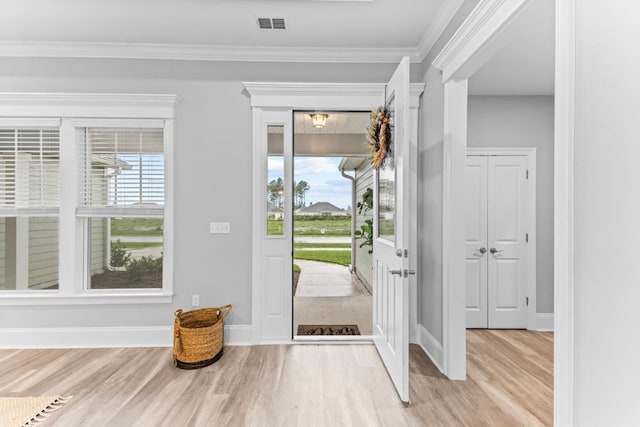 entrance foyer with light wood-type flooring, a wealth of natural light, and crown molding