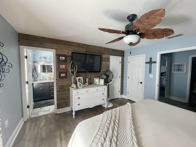 bedroom featuring wooden walls, baseboards, visible vents, dark wood-style flooring, and a sink