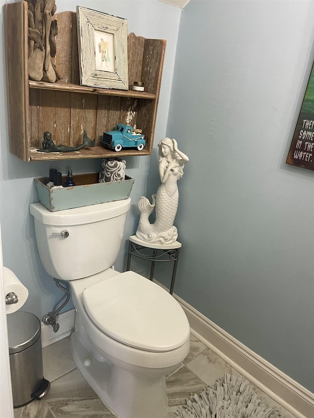 bathroom featuring toilet, marble finish floor, and baseboards