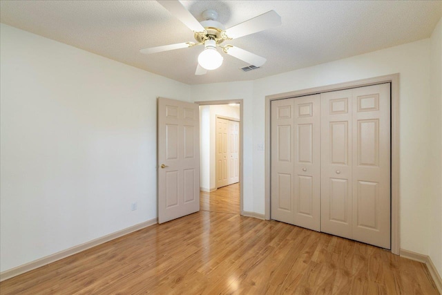 unfurnished bedroom featuring ceiling fan, visible vents, baseboards, light wood-style floors, and a closet