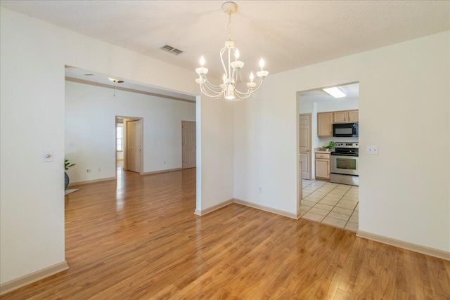 empty room with a textured ceiling, light wood-type flooring, and visible vents