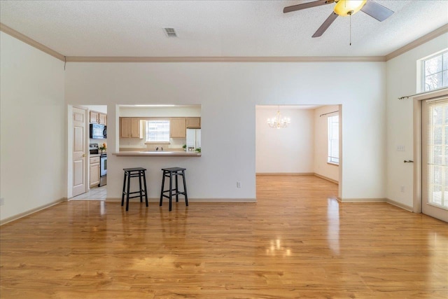 living room with crown molding, a textured ceiling, visible vents, and light wood-style floors