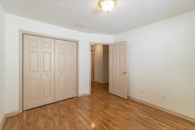 unfurnished bedroom with light wood finished floors, a closet, visible vents, a textured ceiling, and baseboards