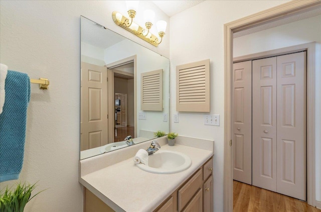 bathroom with a closet, vanity, and wood finished floors