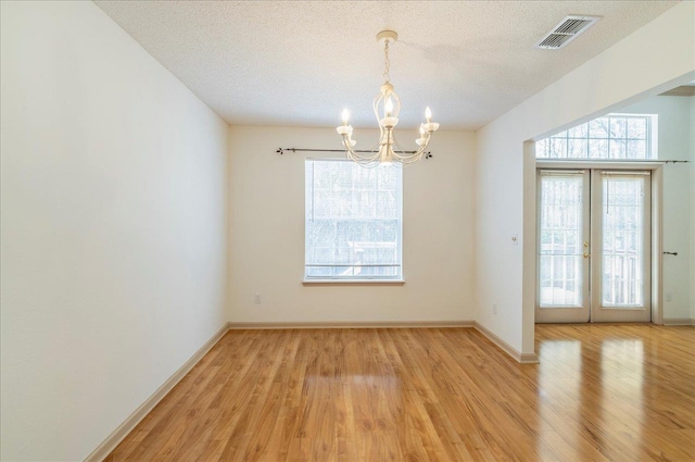 empty room with a healthy amount of sunlight, light wood finished floors, visible vents, and a textured ceiling