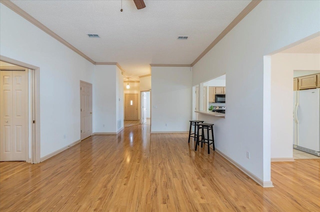 unfurnished living room with ornamental molding, visible vents, light wood-style flooring, and baseboards